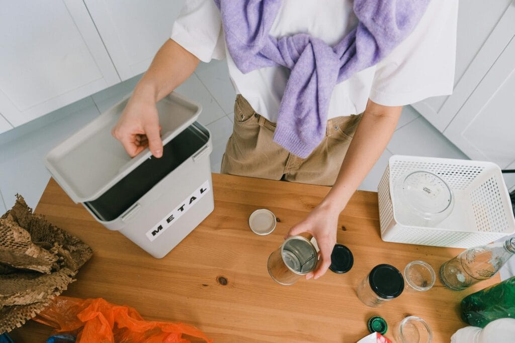 Person sorting metal waste in a kitchen for recycling. Eco-friendly home practice.