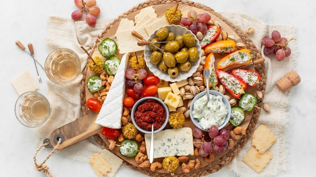 Borrelplank met lekkere hapjes zoals olijven, tomaatjes, kaas, tapas en meer.