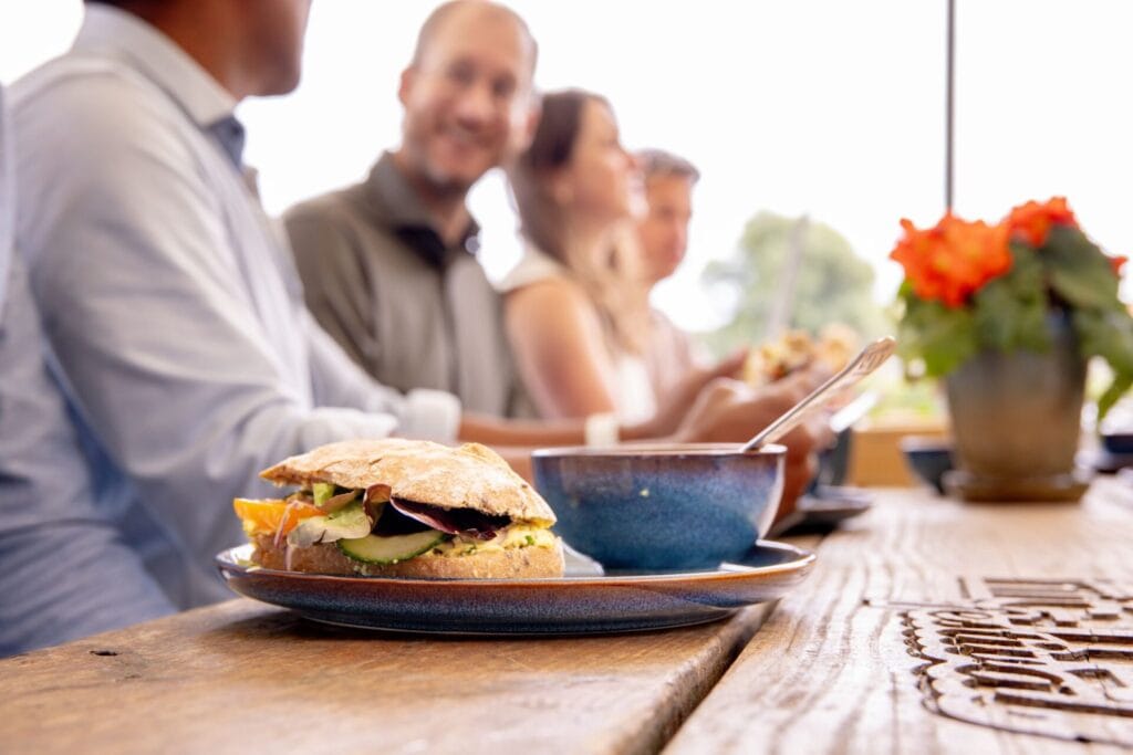 Lunch op het terras met stralende mensen op de achtergrond bij privé vergaderlocatie Ruimte voor Inzicht in Oisterwijk