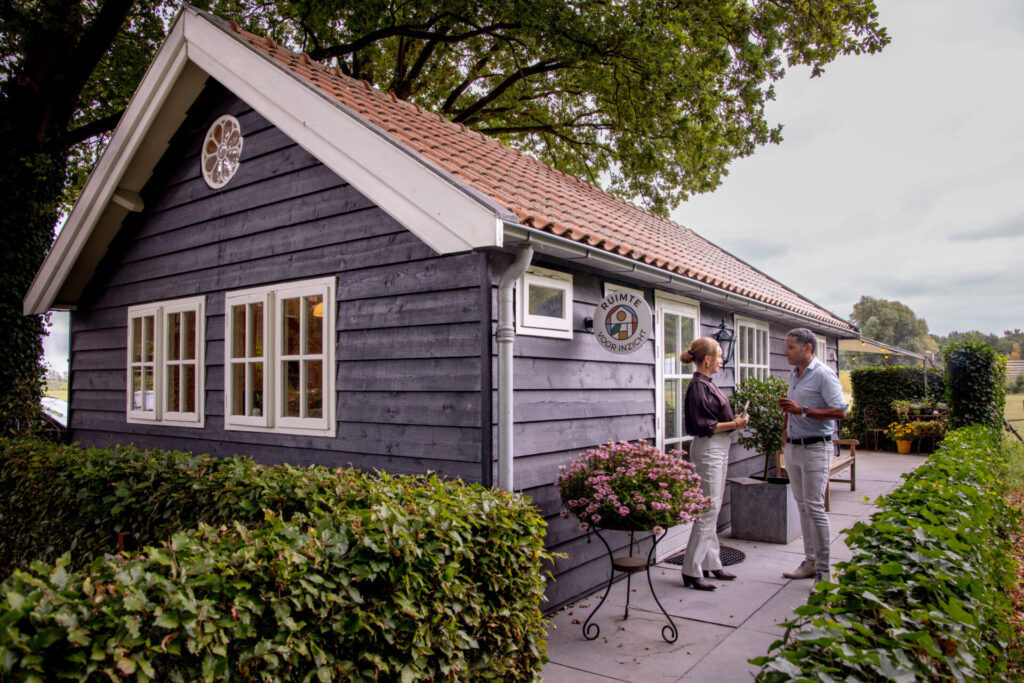 Vooraanzicht van vergaderlocatie Ruimte voor Inzicht met twee mensen die elkaar ontmoeten voor de deur